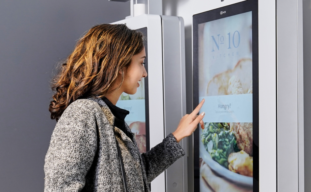 A woman tapping the kiosk screen